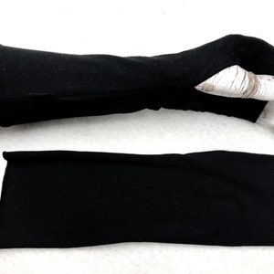 Puede incluir: Un par de guantes negros sin dedos, uno está doblado y el otro está en una mano de maniquí.