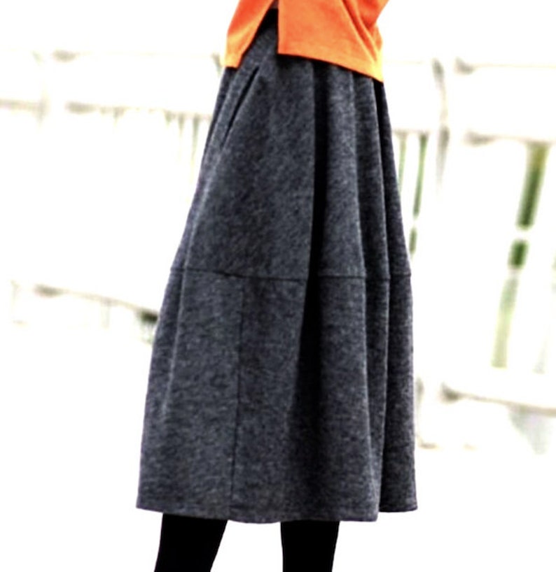 Op de afbeelding: Een grijze midi-rok met een geplooide look. De rok heeft een licht uitlopende pasvorm en is gemaakt van een zachte, comfortabele stof.