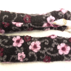 Puede incluir: Un par de guantes sin dedos de color gris oscuro con un estampado floral. Los guantes presentan flores rosas y burdeos con detalles grises. Los guantes están hechos de un material suave y texturizado.