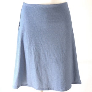 May include: A light blue skirt with a flared A-line silhouette. The skirt is made of a soft, textured fabric and has a simple, elegant design. The skirt is knee-length and suitable for various occasions.