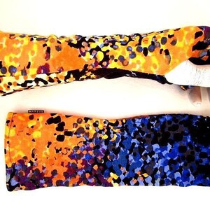Puede incluir: Un par de calentadores de brazos coloridos con un patrón abstracto negro, naranja, amarillo, azul y morado.