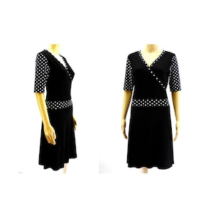 Puede incluir: Un vestido negro de envoltura con lunares blancos. El vestido tiene un escote en V y mangas cortas. El vestido está ajustado en la cintura y se ensancha en el dobladillo.