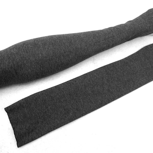 May include: Two grey arm warmers made of a soft, stretchy fabric. The arm warmers are long and narrow, and they are perfect for keeping your arms warm in cold weather.