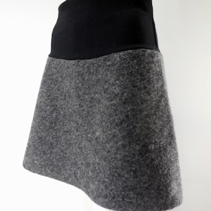 May include: A grey and black skirt with a high waist and a flared silhouette. The skirt is made of a soft, textured fabric.
