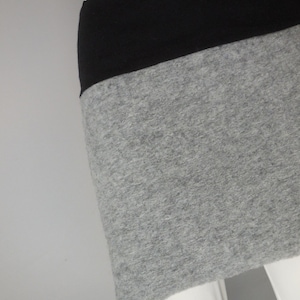 May include: A grey and black skirt with a wide black waistband. The skirt is made of a soft, stretchy fabric.