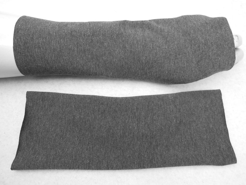 Op de afbeelding: Een paar grijze armwarmers gemaakt van een zachte, rekbare stof. De armwarmers worden getoond gevouwen en uitgevouwen.