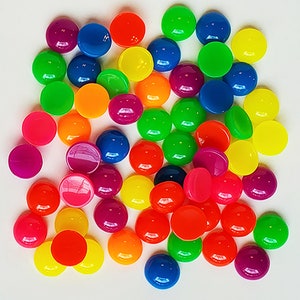 May include: A collection of colorful, glossy, round objects in various shades of red, orange, yellow, green, blue, and purple. The objects are scattered on a white surface, creating a vibrant and playful display.