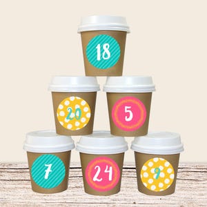 Könnte beinhalten: Ein Stapel aus sechs braunen Pappbechern mit weißen Deckeln. Jeder Becher hat einen bunten Kreisaufkleber mit einer Nummer darauf. Die Zahlen sind 18, 20, 5, 7, 24 und 9.