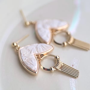 Art Deco oorbellen met een ivoorkleurig kleistukje, kersenbloesemmotief, verguld montuur en pomponvormige hanger.