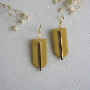 May include: A pair of gold hoop earrings with a mustard yellow rectangular pendant and a gold bar accent.