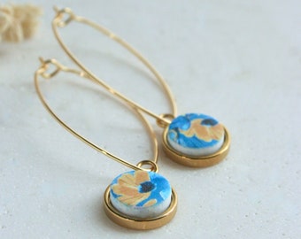 EARRING, long gold plated oval ring and gold plated round pendant with flower pattern on polymer clay piece, blue and yellow.
