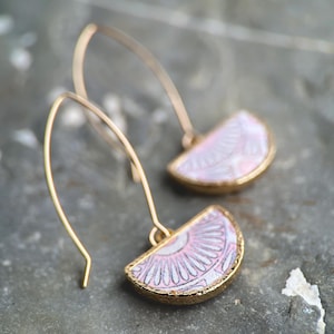 Pode incluir: Um par de brincos de ouro com pingentes de cer&acirc;mica em forma de semic&iacute;rculo com padr&atilde;o rosa e branco.