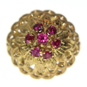 May include: A gold ring featuring a cluster of pink gemstones set in a textured, floral design.