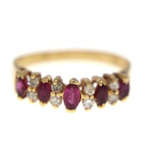May include: A gold ring featuring alternating oval-cut rubies and small round diamonds. The gemstones are set in a row along the band. The ring is set against a white background.