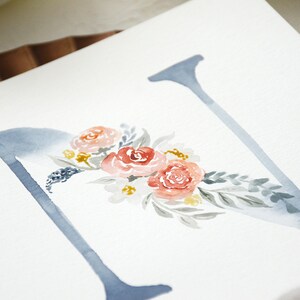 May include: Watercolor painting of the letter N with a floral design. The letter is painted in a light blue color and the flowers are in shades of pink, red, and yellow.