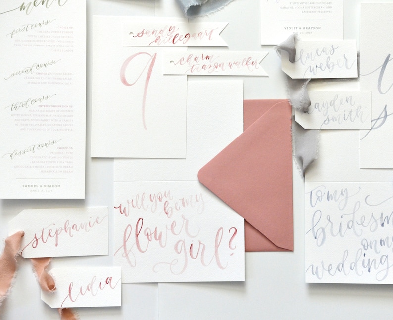 Puede incluir: Un conjunto de tarjetas y sobres relacionados con la boda con caligraf&iacute;a en tonos rosa y gris. Las tarjetas incluyen un men&uacute;, un n&uacute;mero de mesa, una solicitud de dama de honor y una solicitud de dama de honor. El texto en las tarjetas incluye "&iquest;Quieres ser mi dama de honor?" y "Para mis damas de honor".