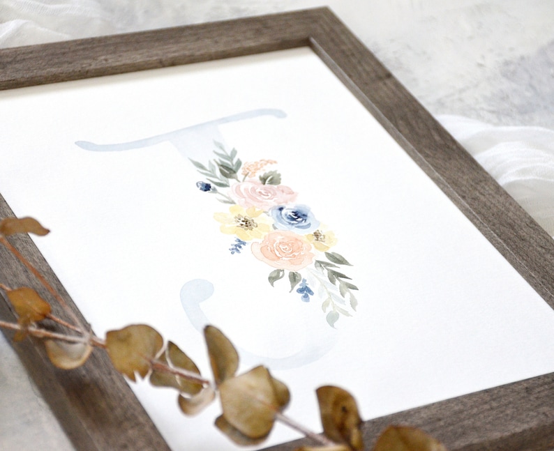 May include: A watercolor painting of the letter "J" with a floral design. The flowers are in shades of pink, yellow, and blue. The background is a light blue.