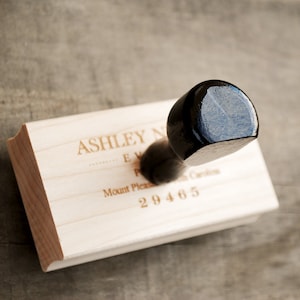 Pode incluir: Um suporte de correio de parede de madeira com uma maçaneta preta. O suporte tem o texto "Ashley N... E... P... Mount Pleasant, S. Carolina 29465" gravado nele.
