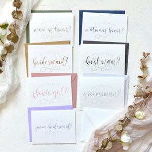 May include: Set of eight cards with different wedding party titles, including maid of honor, matron of honor, bridesmaid, best man, groomsman, flower girl, and junior bridesmaid. The cards are printed on white cardstock with calligraphy-style lettering.