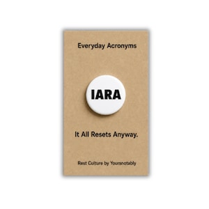May include: A circular white pin-back button featuring the black text IARA centered on a rectangular tan card. The card displays the text Everyday Acronyms at the top, It All Resets Anyway. below the button, and Rest Culture by Yoursnotably at the base.