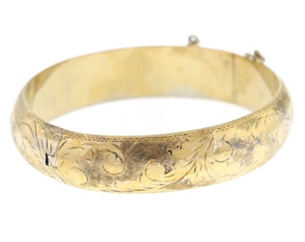 Könnte beinhalten: Ein goldenes Armreif-Armband mit einem komplizierten floralen Design. Das Armband ist aus glattem, poliertem Metall gefertigt und hat einen Scharnierverschluss.