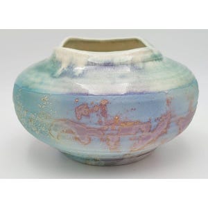 May include: A ceramic vase with a rounded, bulbous body and a wide, open mouth. The surface features a blended glaze of soft blue, pale purple, and creamy white tones, with textured, mottled patches of metallic copper and gold accents throughout.