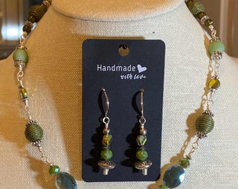 Könnte beinhalten: Ein grünes und silbernes Halsketten- und Ohrring-Set mit grünen und blauen Perlen. Das Etikett lautet "Handmade with love".