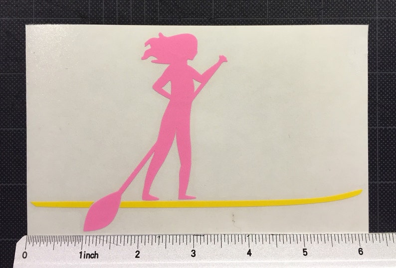 May include: Pink silhouette of a person paddleboarding on a yellow surfboard. The person is holding a paddle in their right hand.