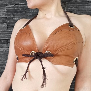 May include: A brown leather halter top with a lace-up front and gold metal accents.