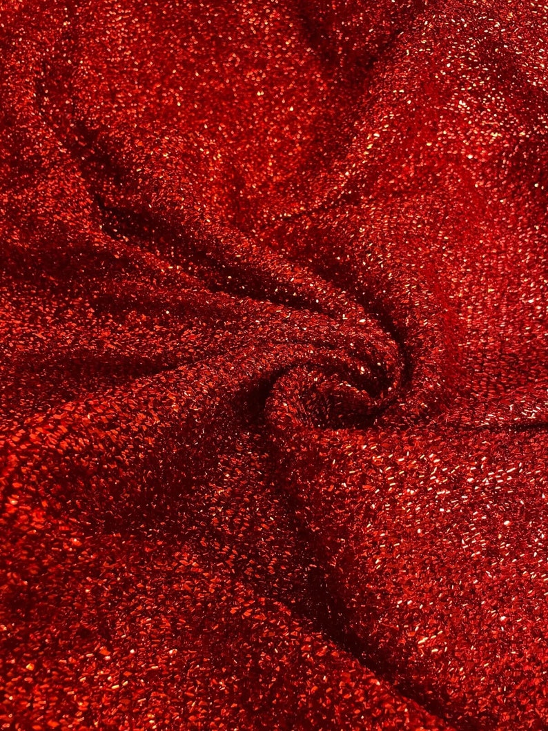 May include: Red sparkly fabric with a textured surface. The fabric is wrinkled and folded.