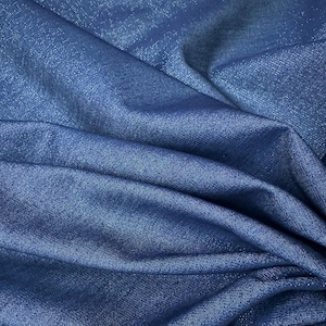 May include: Close-up of a textured, deep blue fabric with subtle shimmering highlights. The fabric is draped, creating soft folds and shadows. The material appears to be a medium weight, suitable for apparel or home decor.