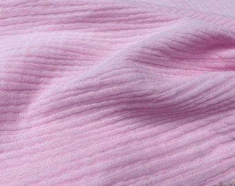 May include: Close-up of a soft, pink fabric with a textured, crinkled surface.
