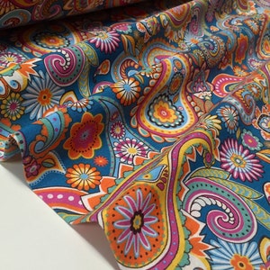 May include: A teal blue fabric with a paisley pattern in shades of orange, yellow, pink, and green. The fabric has a white background and is perfect for crafting projects.