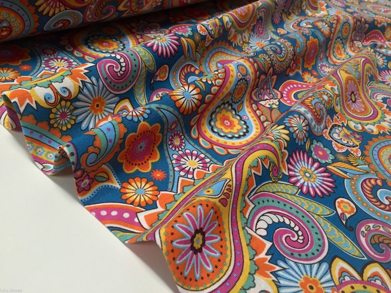 May include: A teal blue fabric with a paisley pattern in shades of orange, yellow, pink, and green. The fabric has a white background and is perfect for crafting projects.