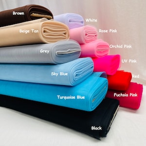 May include: A stack of 12 rolls of tulle fabric in various colours, including brown, beige tan, white, rose pink, grey, sky blue, turquoise blue, black, orchid pink, UV pink, red, and fuchsia pink.
