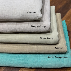 Puede incluir: Cinco muestras de tela apiladas una encima de la otra. Las muestras son de los siguientes colores de arriba a abajo: crema, gris topo, gris salvia, topo y turquesa jade.