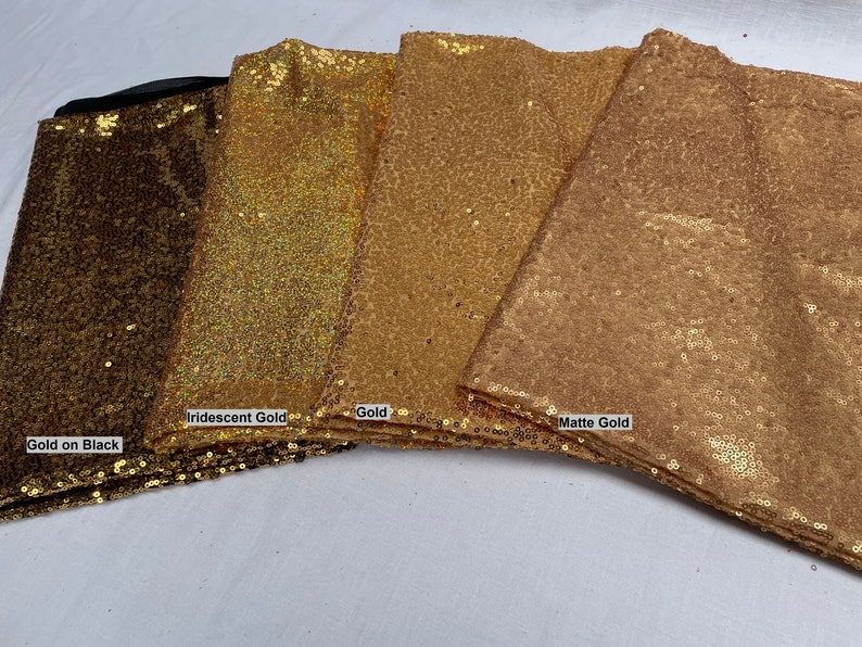 Pode incluir: Close-up de quatro tecidos de lantejoulas douradas diferentes. Os tecidos s&atilde;o rotulados como "Gold on Black", "Iridescent Gold", "Gold" e "Matte Gold". Os tecidos est&atilde;o dobrados e empilhados, mostrando suas diferentes texturas e cores.