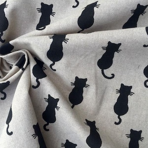 Puede incluir: Una tela beige con un patr&oacute;n repetido de siluetas de gatos negros. Los gatos miran hacia la derecha y tienen un dise&ntilde;o simple.