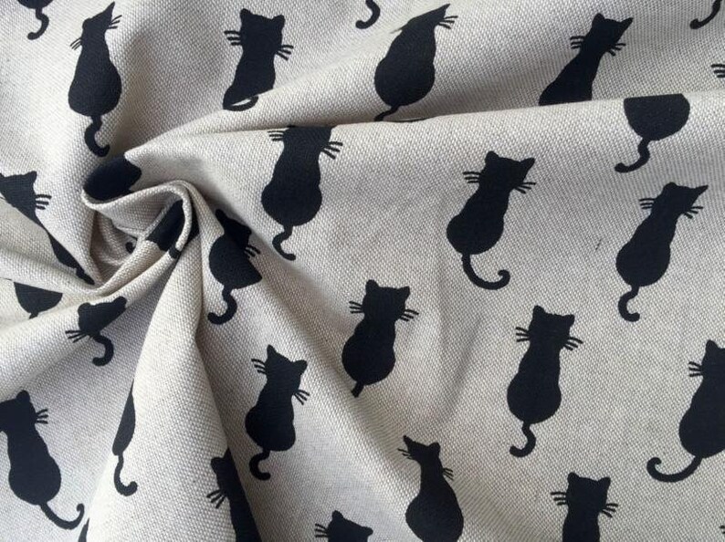 Puede incluir: Una tela beige con un patr&oacute;n repetido de siluetas de gatos negros. Los gatos miran hacia la derecha y tienen un dise&ntilde;o simple.