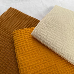 Puede incluir: Tres muestras de tejido de tejido de waffle en marr&oacute;n, amarillo mostaza y crema.