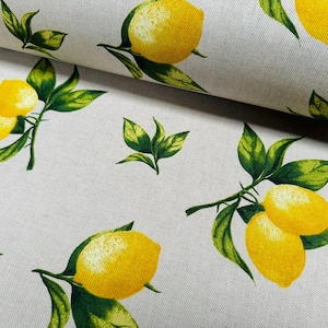 Può includere: Primo piano di un tessuto con un motivo ripetuto di limoni gialli e foglie verdi su sfondo beige chiaro. I limoni hanno riflessi bianchi e le foglie un effetto acquerello.