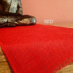 May include: Red burlap table runner with frayed edges. The runner is on a wooden surface. RED.
