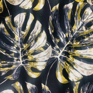 May include: Black fabric with a large-scale print of gold and gray tropical leaves.