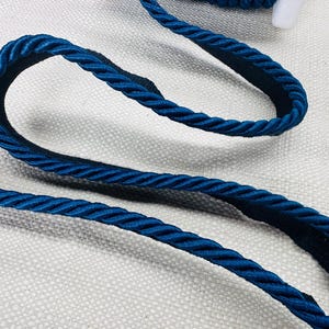 May include: Teal blue braided trim with a soft, slightly shiny finish. The trim is thick and has a rope-like texture.