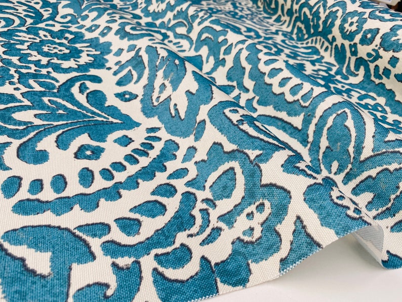 May include: Teal and white fabric with a repeating floral pattern. The fabric has a textured surface.