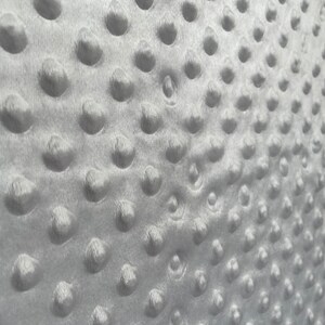 May include: Close-up of a white, textured fabric with a repeating pattern of small, raised circles.