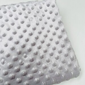 May include: A soft, gray, textured fabric with a subtle sheen. The fabric has a raised dot pattern.