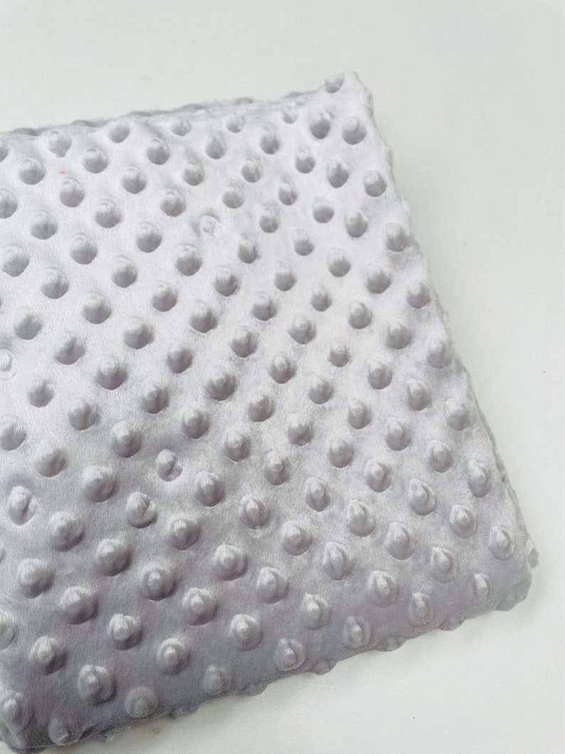 May include: A soft, gray, textured fabric with a subtle sheen. The fabric has a raised dot pattern.