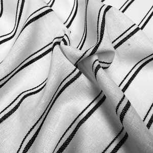 May include: White fabric with black stripes. The fabric is wrinkled and has a soft texture.
