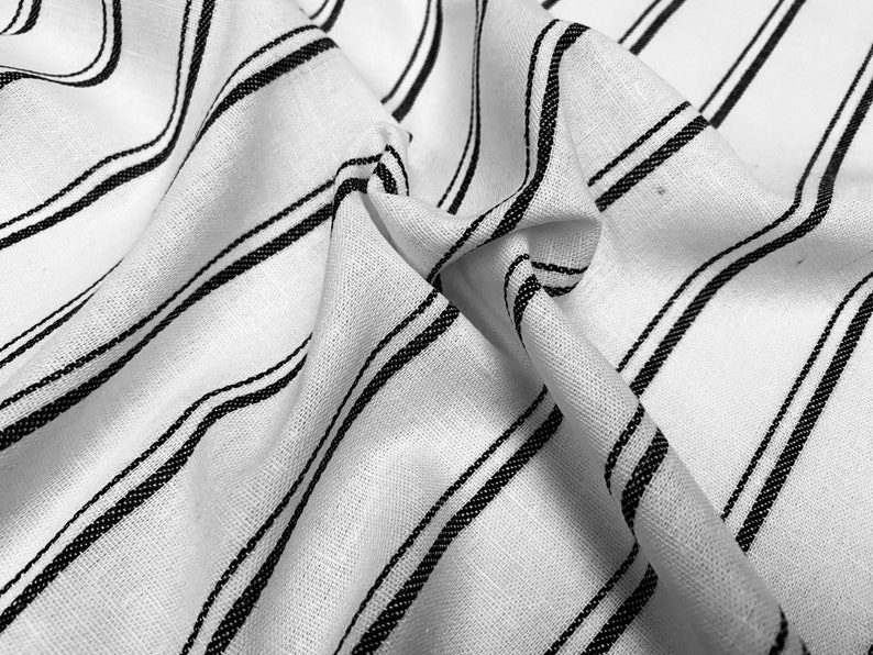 May include: White fabric with black stripes. The fabric is wrinkled and has a soft texture.